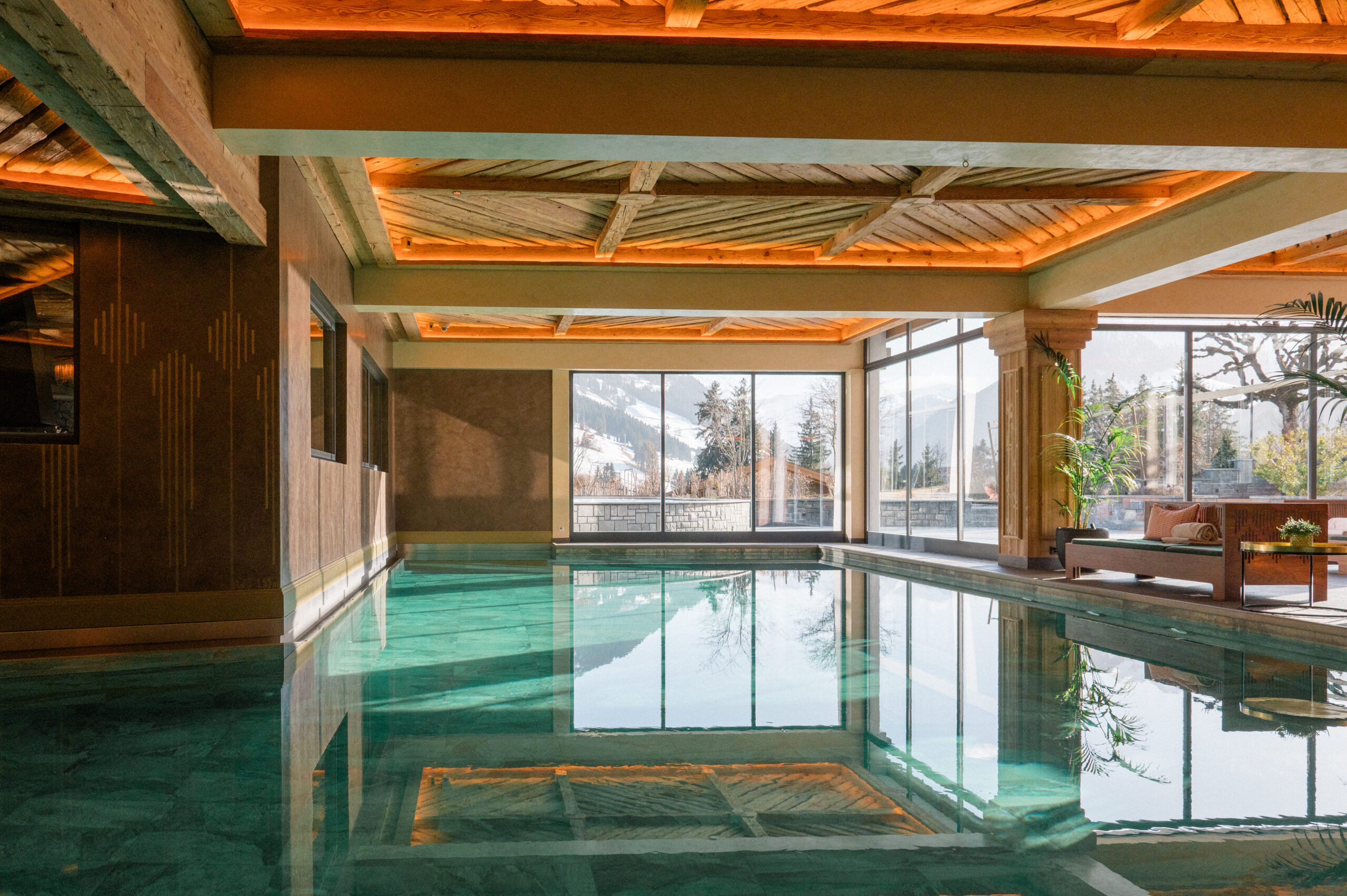 Indoor Alpine spa pool with timber architecture and snowy mountain views